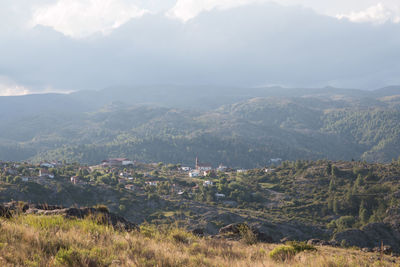 Aerial view of townscape by mountains against sky