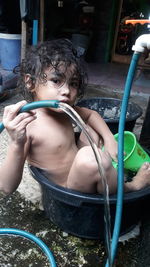 Full length of shirtless boy drinking water in yard