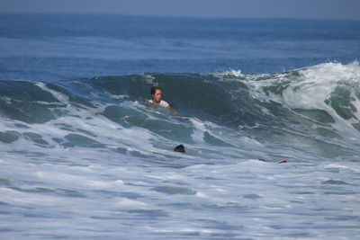 Man surfing in sea against sky