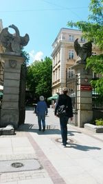 Rear view of people walking on road along buildings