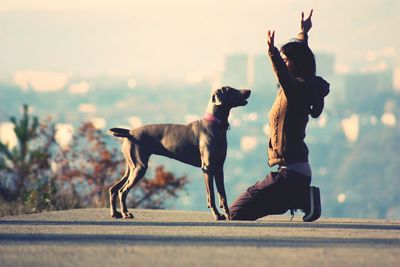 Side view of woman playing with dog on road