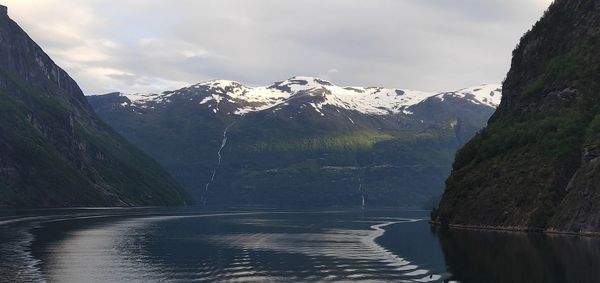 Scenic view of lake by snowcapped mountains against sky