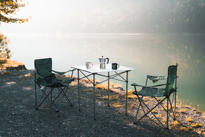 Empty chairs and tables and table by sea