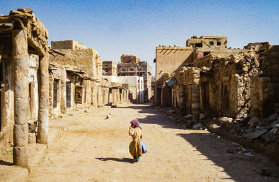 Woman on old ruins against sky