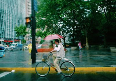 People riding bicycle on wet street during rainy season