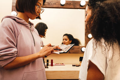 Woman applying eyeshadow to female