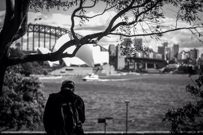 Man standing by tree in city against sky