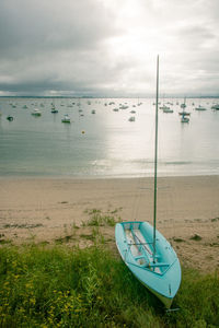 Sailboat moored on beach against sky