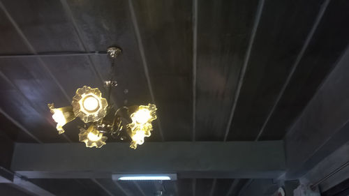 Low angle view of illuminated light bulb hanging from ceiling