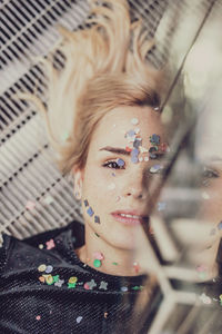 Portrait of woman with confetti on face lying on floor