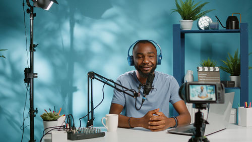 Happy man filming through camera at desk