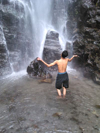 Eye angle view of young men standing in waterfall