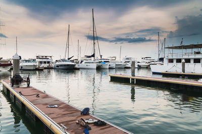 Sailboats moored at harbor against sky