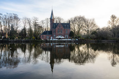 Refelction of historical building and trees in water against sunset