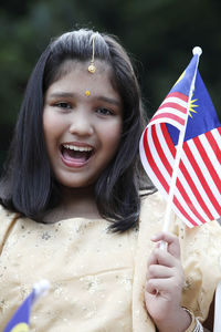 Portrait of smiling girl holding malaysia flag