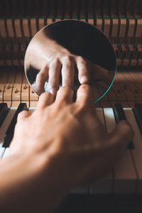 Cropped hand playing piano with reflection on mirror