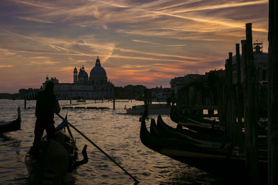 Silhouette of boats in city at sunset