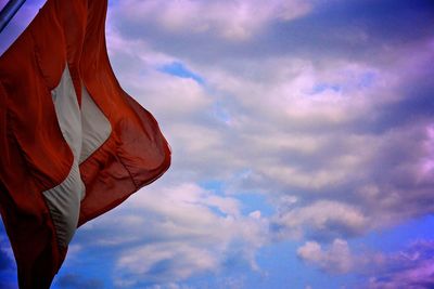 Low angle view of swiss flag against cloudy sky