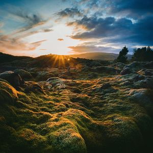 Scenic view of dramatic landscape against cloudy sky during sunrise