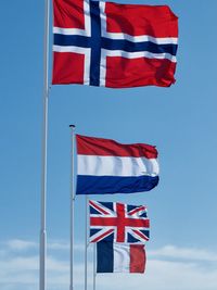 Low angle view of flags against blue sky