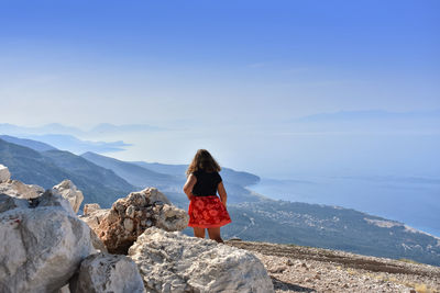 Rear view of man standing on rocks against mountain