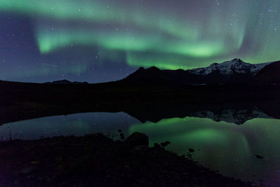 Scenic view of lake and mountains against sky at night