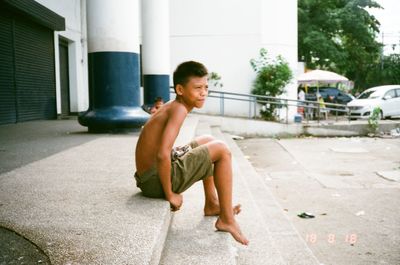 Full length of shirtless boy on street in city