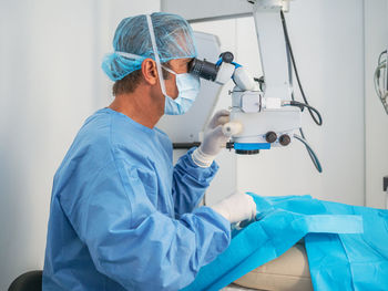 Mature doctor in mask and uniform preparing surgery tools while working in modern hospital