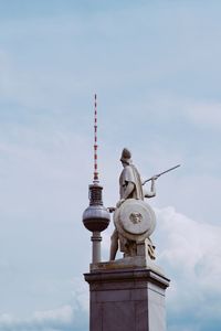 Low angle view of statue and tower against sky