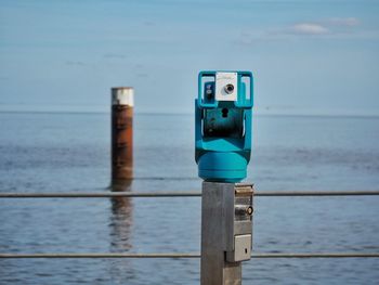 Lifeguard hut on wooden post in sea against sky