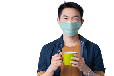 Portrait of young man drinking glass against white background