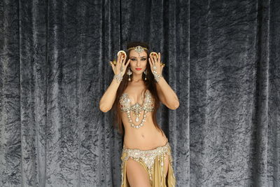 Portrait of a beautiful young woman standing against wall