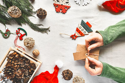 Woman's hands holding christmas gift wrapped in craft paper on the table with christmas decoration