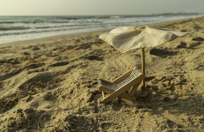 Deck chairs on sand at beach against sky