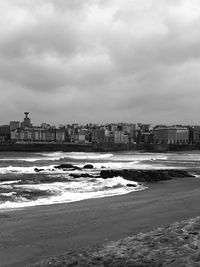 Sea and buildings in city against sky