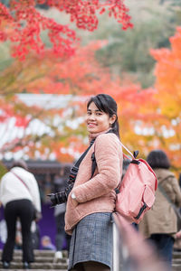 Portrait of woman standing by autumn leaves