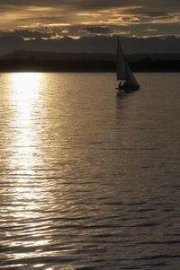 Sailboat sailing on sea against sky during sunset