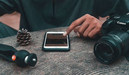 Midsection of man using mobile phone on table