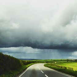 Country road against cloudy sky