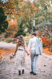 Rear view of friends walking on sidewalk during autumn