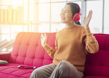 Smiling young woman sitting on sofa