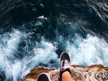 Low section of person on cliff over sea