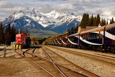 Train on railroad track by snowcapped mountains against sky