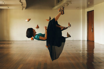 Optical illusion of butterflies holding girl in mid-air at room