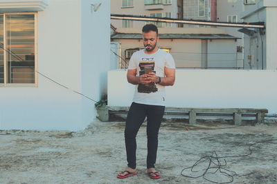 Man smoking cigarette while using mobile phone on building terrace