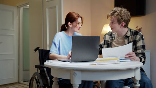 Young couple working by table at home