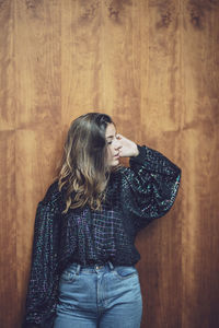  young woman looking away standing against wooden wall