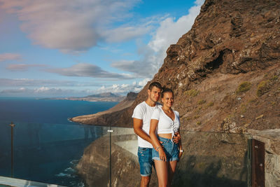 Side view of young woman standing against mountain