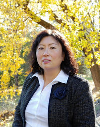 Portrait of beautiful businesswoman standing against trees