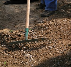 Low section of man working field through rake